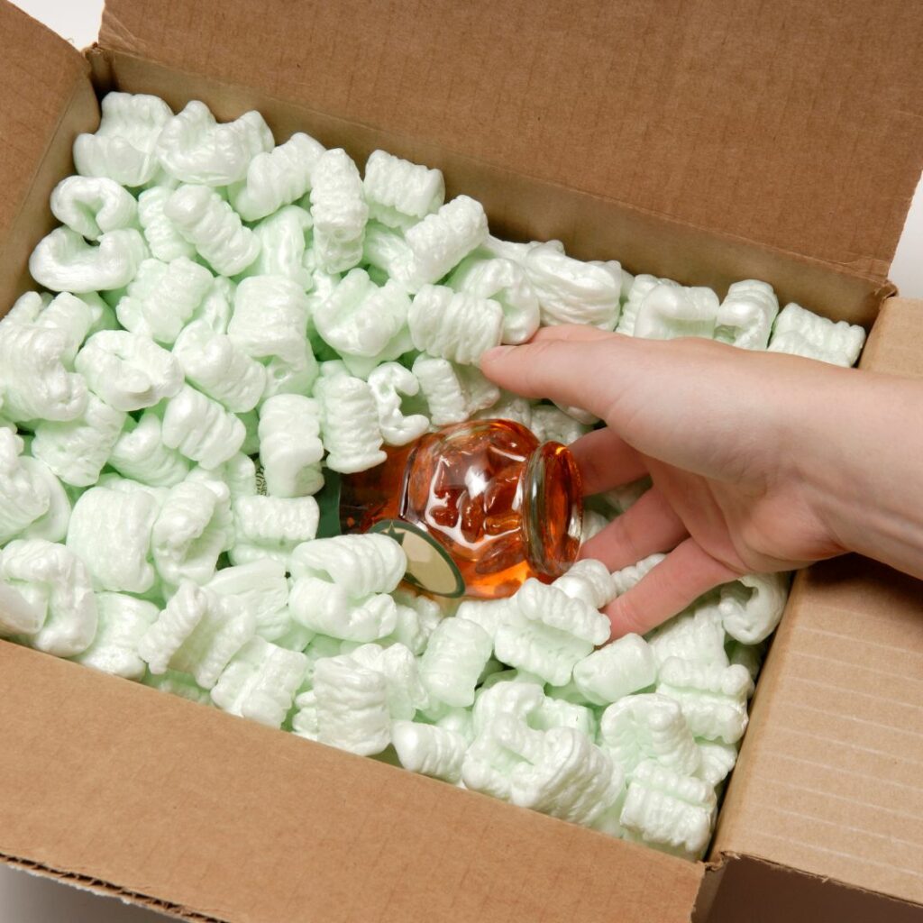 Packing fragile item in box of packing peanuts