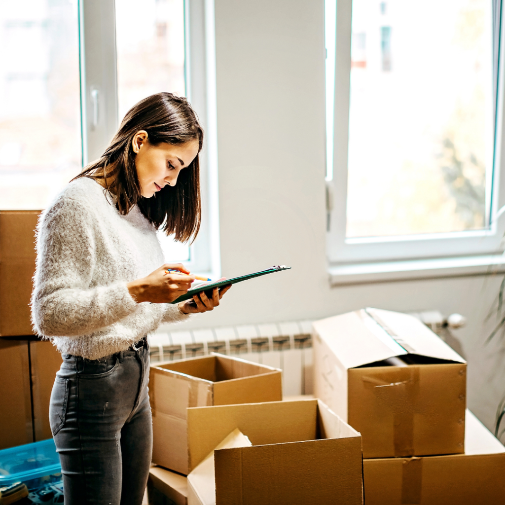 Woman looking over packing list in a room full of moving boxes