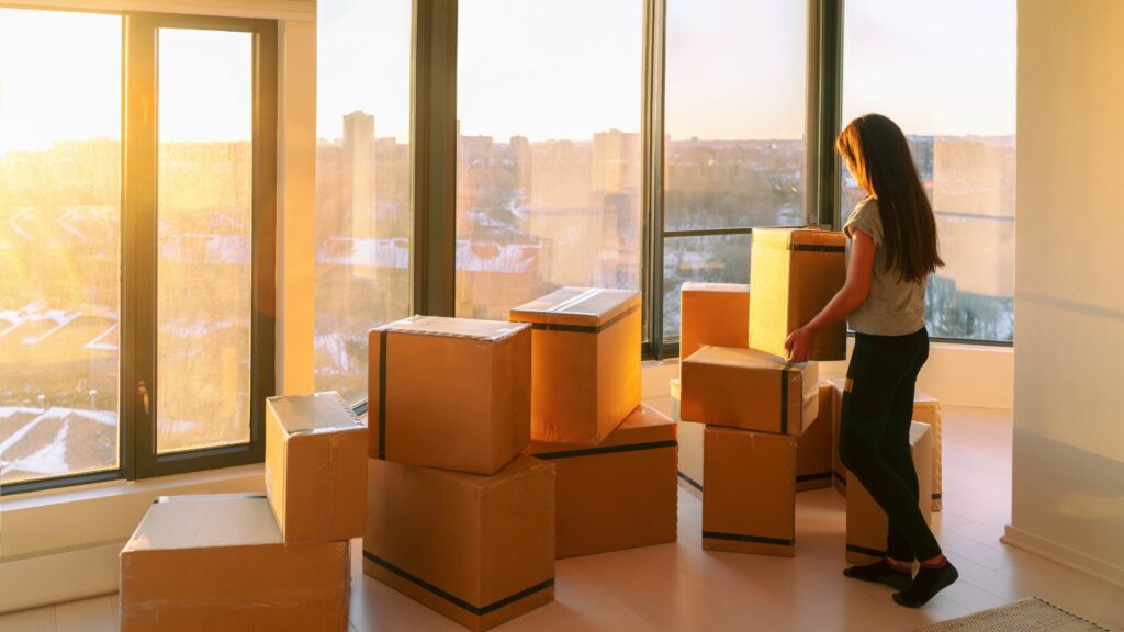 Woman unpacking boxes in apartment with city skyline view