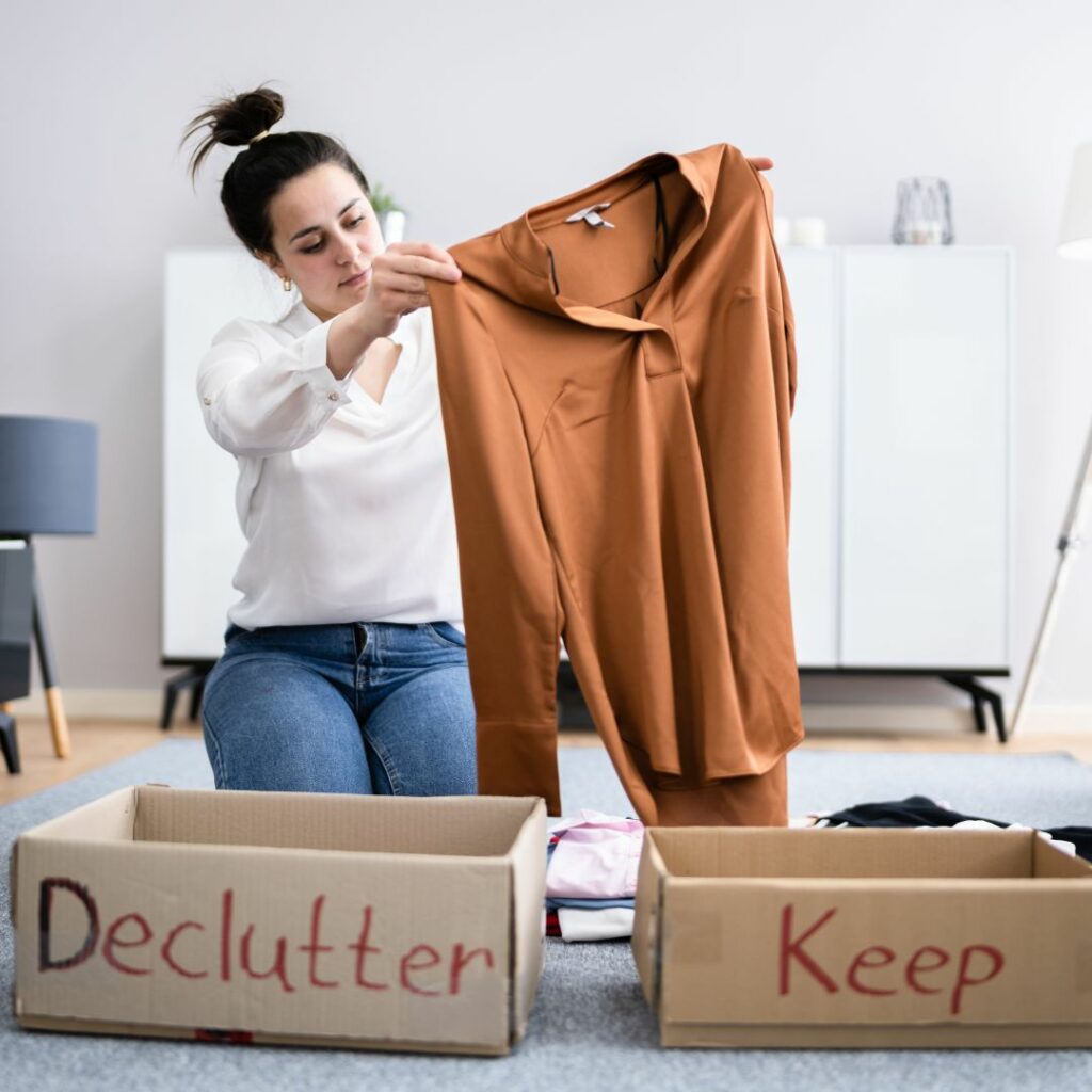 Woman holding up shift in front of two boxes, labeled "Declutter" and "Keep"