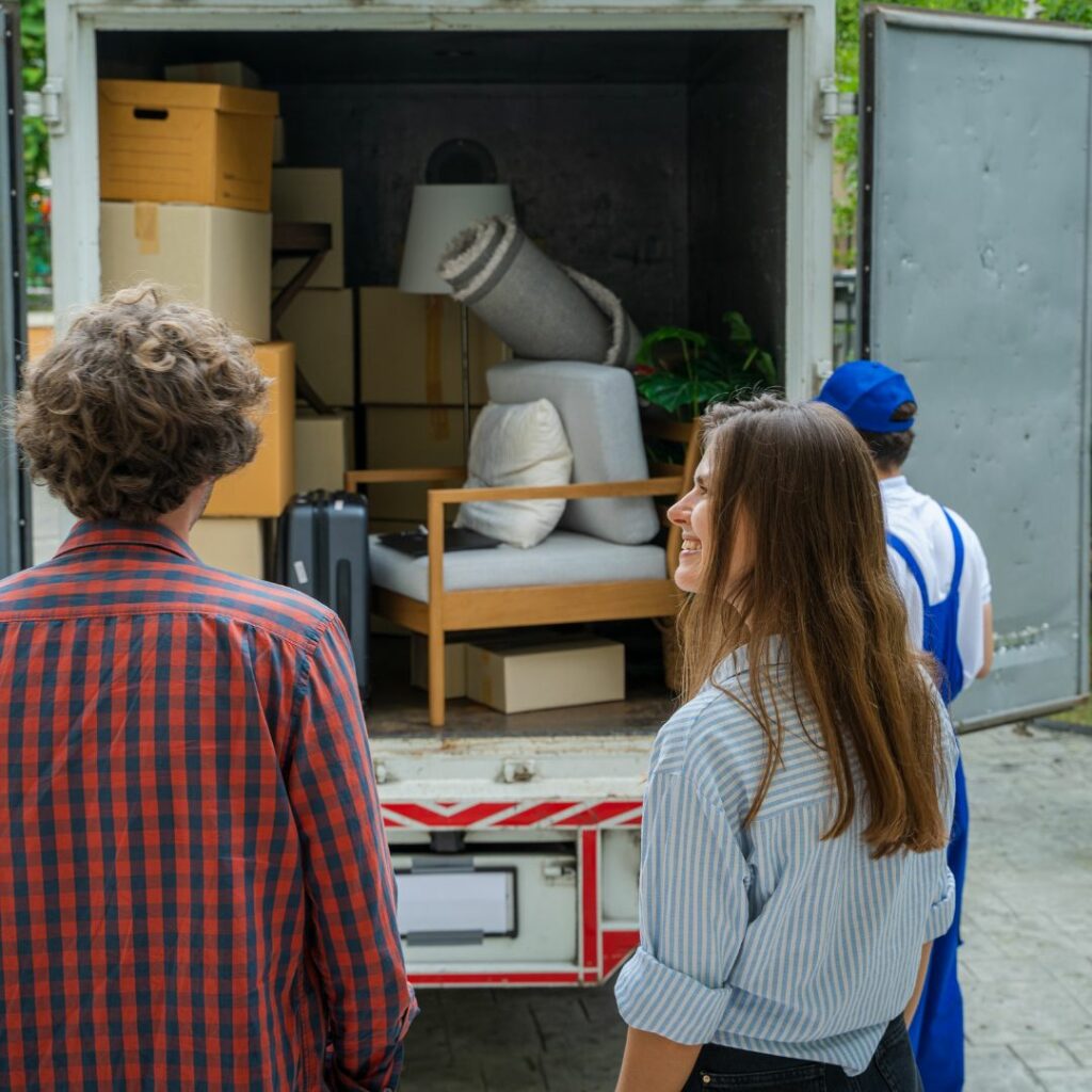 Couple watching movers pack up a moving truck