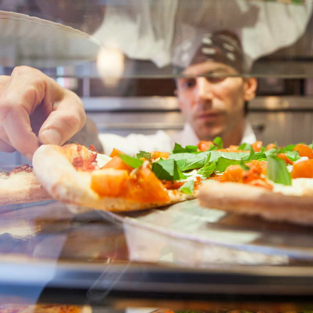 a chef prepping a slice of pizza for a customer